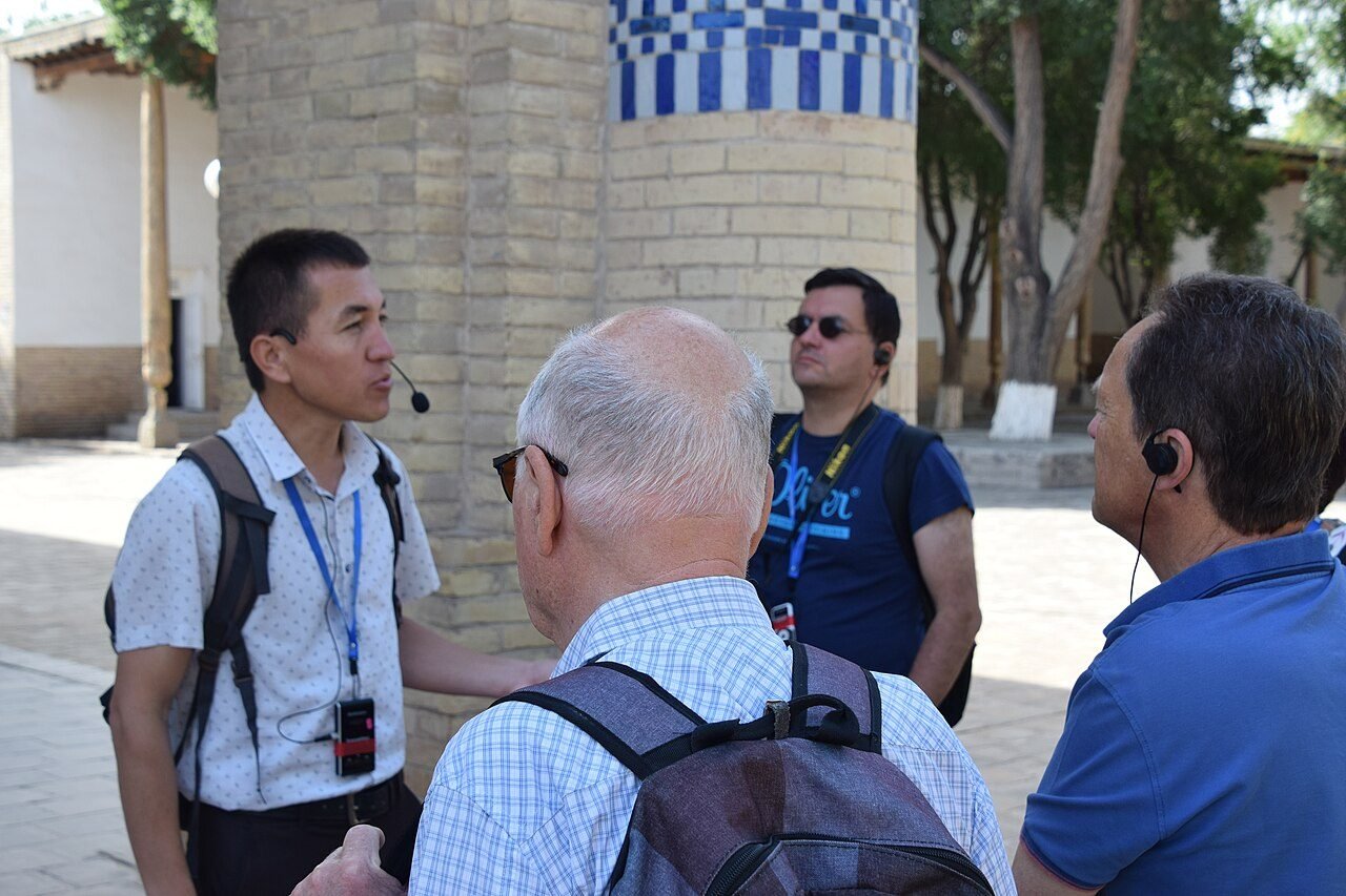 Licensed tour guide explaining a historic monument to travelers in Uzbekistan — Dunya Travel